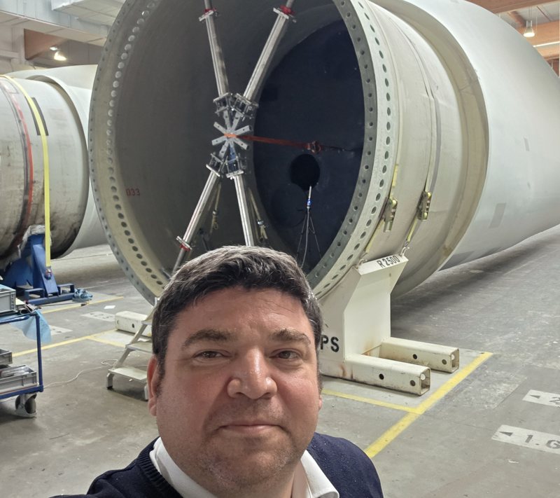 Daniel Hein, Managing Partner of Adoxin, in front of a wind turbine blade in a manufacturing hall