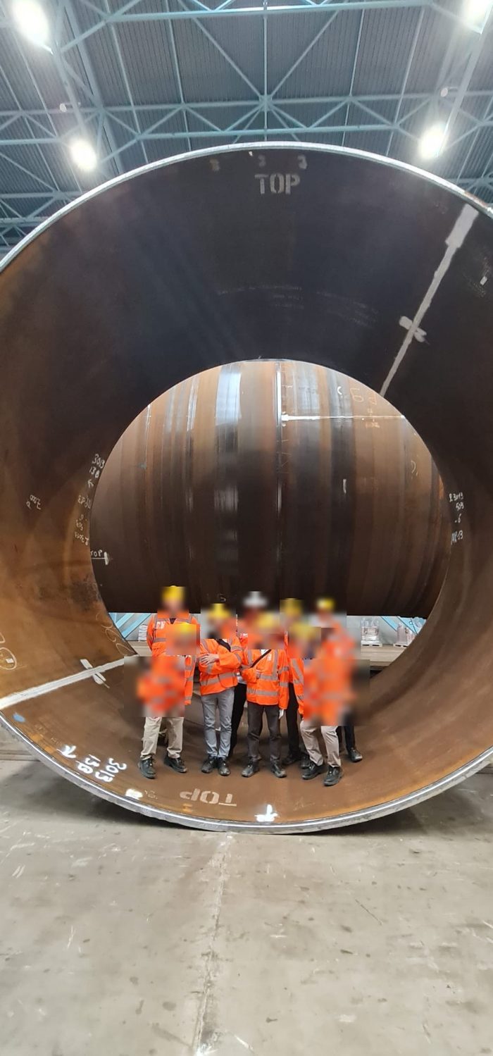 Group of participants in safety vests standing inside an XXL monopile foundation